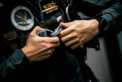 Een vliegenier in militair tenue maakt zijn riemen vast.