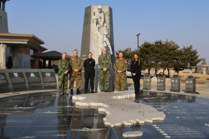Twee Nederlandse en drie Canadese militairen en een Amerikaanse burger voor het Koreaanse oorlogsherdenkingsmonument op Camp Humphreys.