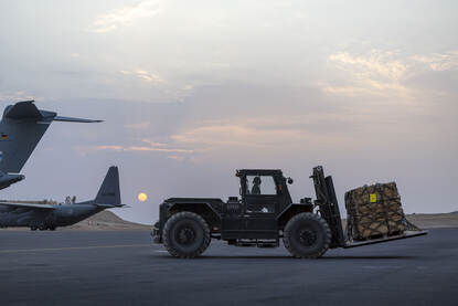 Links wordt vracht in een Duitse A400M geschoven en rechts rijdt een heftruck over het platform.
