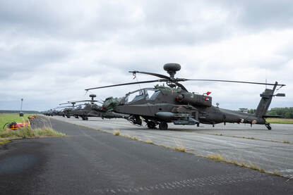 Chinooks en Apaches achter elkaar in een lange rij opgesteld.