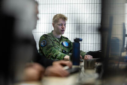 Foto van een militair die naar zijn computer kijkt