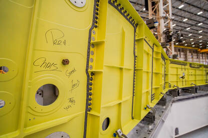 Een grote gele metalen balk met daarop links diverse namen geschreven.