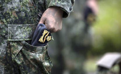 Baret gestoken in broekzak van het gevechtstenue.