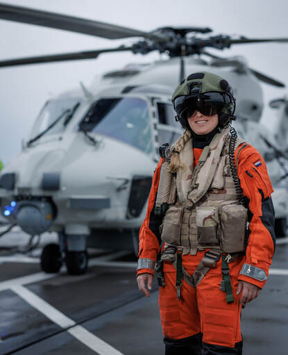 Sergeant Jolien staat op het vliegdek van Zr.Ms. van Amstel voor de NH90 klaar om aan boord te stappen.