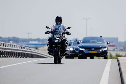 Motorrijder KMar met voertuigen erachter.