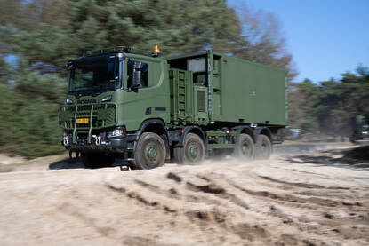 Scania Gryphus van de Nederlandse krijgsmacht rijdt door duinzand.