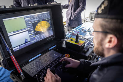 Een medewerker van de koninklijke marine bekijkt beelden op een scherm.