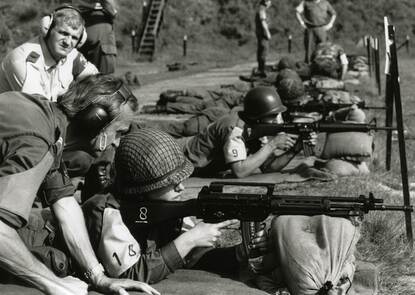 Militairen liggende achter geweren op schietbaan.