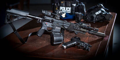 HK 416 met daarvoor een Glock 17 en daarachter helm en scherfvest.