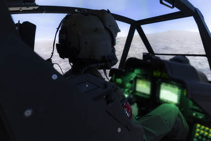 Apache-vlieger in simulator oefent in virtuele wereld een missie.
