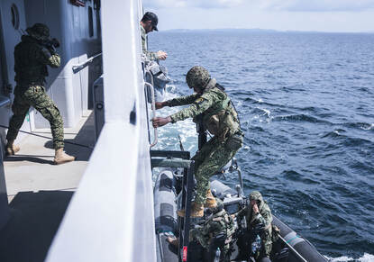 Colombiaanse mariniers klimmen aan boord van het schip en lopen met getrokken wapen over de dekken.