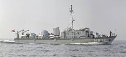 Een grijs schip op een kalme zee in zwart-wit.